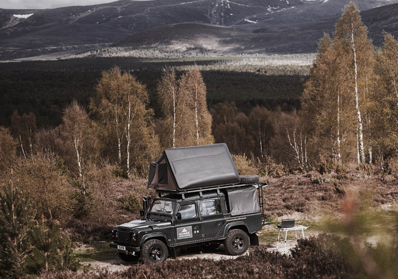 A Land Rover with a roof tent belonging to Nomadic Scotland parked in stunning winter countryside in Scotland