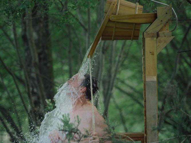 A person under cold water being spilled from a bucket during cold water therapy