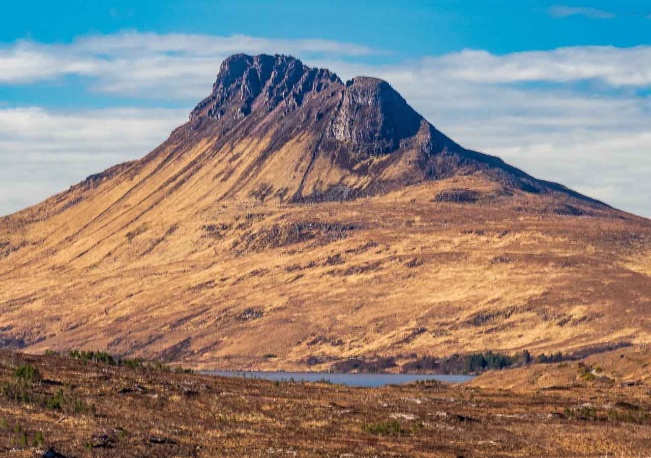 Stac Pollaidh view with a blue sky behind the mountain.