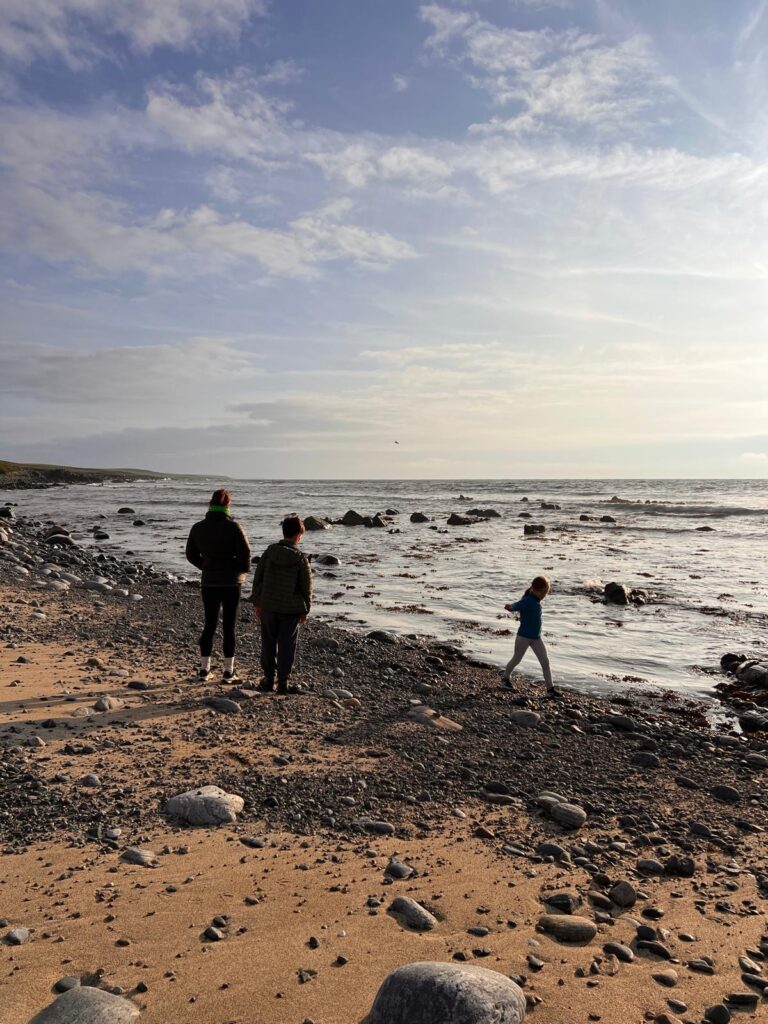 Family stood watching sunset on a beach, Isle of Lewis