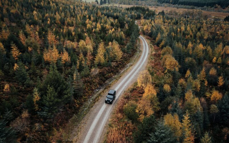 Aerial view of a Land Rover Defender on a forest track in autumn