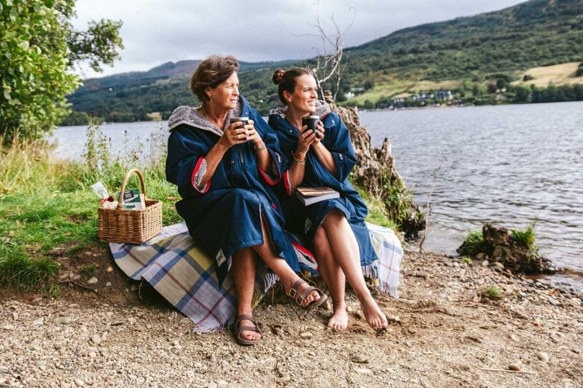 highland-reset-03-nomadic-highlands Two people sitting beside a Highland loch with a drink