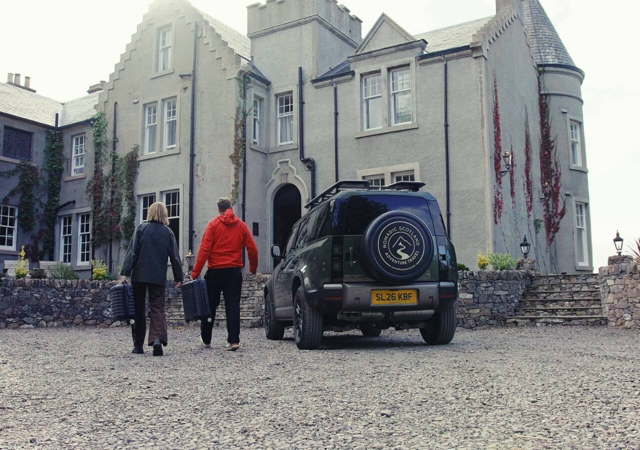 A couple walking to their Land Rover Defender outside a stone building